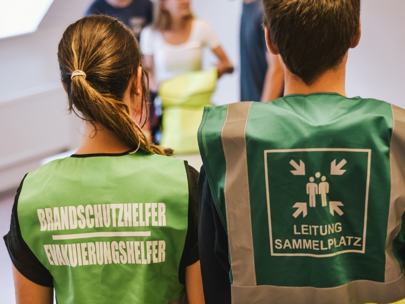 Mitarbeiter mit einer Evakuierungshelfer Weste, beim Evakuieren